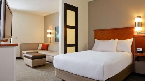 a hotel room with a bed and a couch at Sonesta Select Atlanta Duluth in Duluth