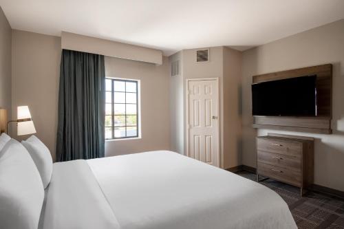 a hotel room with a bed and a flat screen tv at Staybridge Suites Phoenix Glendale Sports Dist by IHG in Glendale