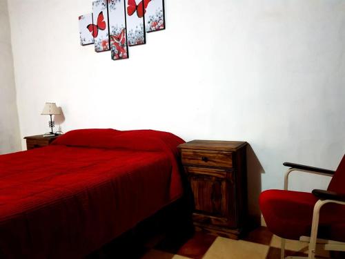 a bedroom with a red bed and a red chair at Posada Villa Aurorita in Famatina