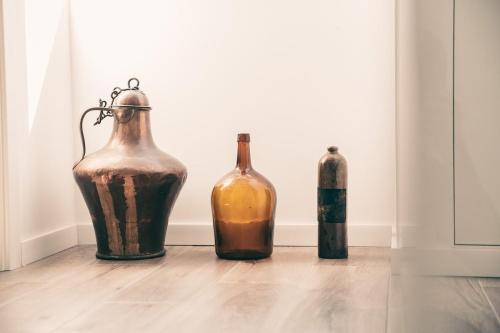 three bottles and a vase sitting on a floor at A Casa da Cerca in Almodôvar