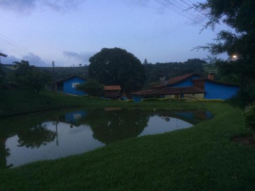 a pond in the middle of a field with houses at Pousada Som das Águas Bueno Brandão in Bueno Brandão