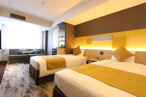 東京にあるKOKO HOTEL Tsukiji Ginzaのベッド2台とソファがあるホテルの部屋