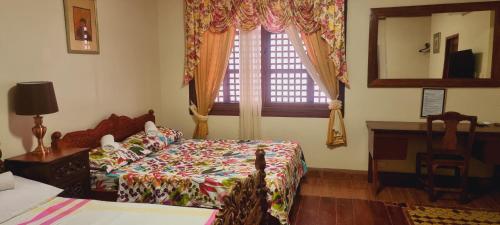a bedroom with a bed and a mirror and a window at Casa Familya in Batac