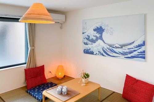 a living room with a table and a large wave on the wall at japan house shinkoiwa in Tokyo