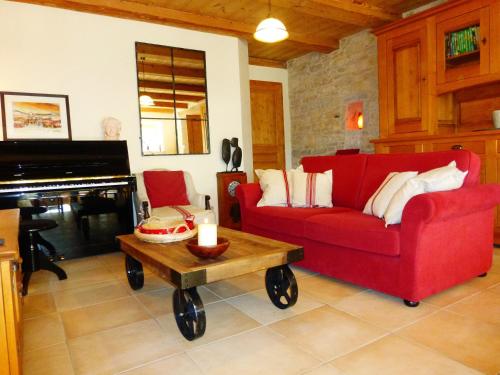 a living room with a red couch and a piano at Chambres d'hôtes Béred Vuillemin in Baume-les-Dames
