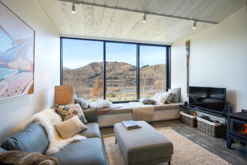 a living room with a couch and a large window at The Cottages at Lake Hayes in Queenstown