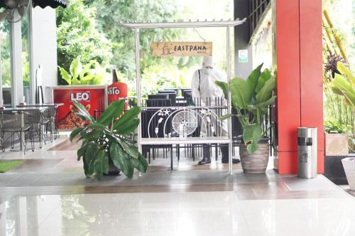 a man is standing outside of a restaurant with plants at Eastpana Hotel - SHA Extra Plus in Si Racha