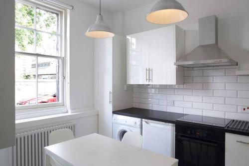 eine weiße Küche mit weißen Geräten und einem Fenster in der Unterkunft Beautiful Scandi-Inspired one bed in Stockbridge in Edinburgh