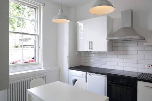 a white kitchen with white appliances and a window at Beautiful Scandi-Inspired one bed in Stockbridge in Edinburgh