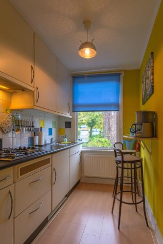 a kitchen with yellow walls and white cabinets and a stool at Familie Quellhorst in Leiden