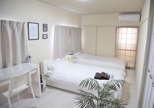 a white bedroom with a white bed and a desk at Osaka U-Shuku in Osaka