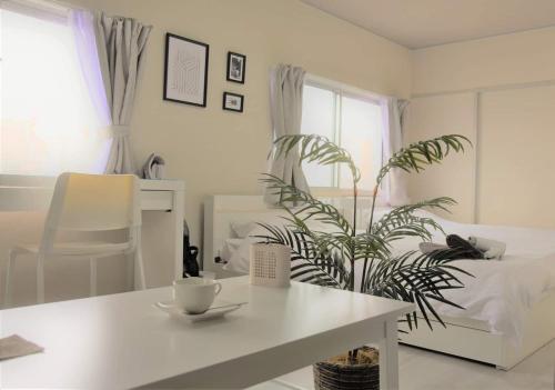 a white bedroom with a table and a plant at Osaka U-Shuku in Osaka