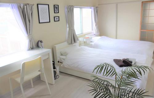 a bedroom with a white bed and a desk and a plant at Osaka U-Shuku in Osaka