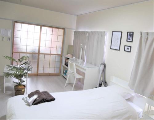 a white bedroom with a white bed and a desk at Osaka U-Shuku in Osaka