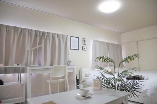 a white room with a table and a plant at Osaka U-Shuku in Osaka