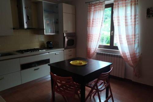 eine Küche mit einem Tisch, 2 Stühlen und einem Fenster in der Unterkunft Appartamento nel verde tra Cinque Terre e Versilia in Barbarasco