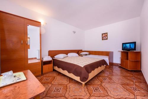 a bedroom with a bed and a tv and a table at Vilele violeta in Mamaia Sat/Năvodari
