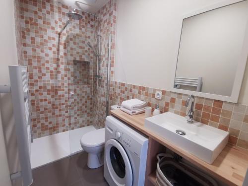 een badkamer met een wasmachine en een wastafel bij Appartement Escapade Vitaminée - Maison d'Aligre in Marans