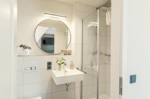 a white bathroom with a sink and a mirror at Das Hölderlein - Altstadthotel in Nürtingen