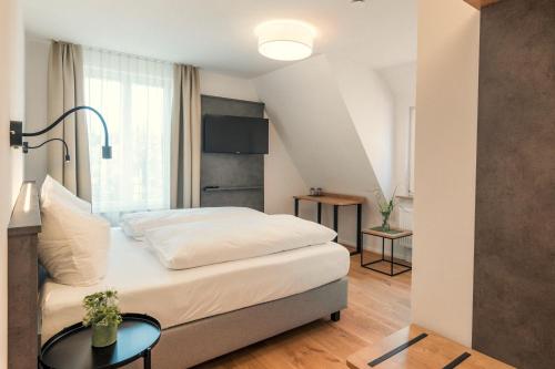 een slaapkamer met een groot bed en een tafel bij Das Hölderlein - Altstadthotel in Nürtingen