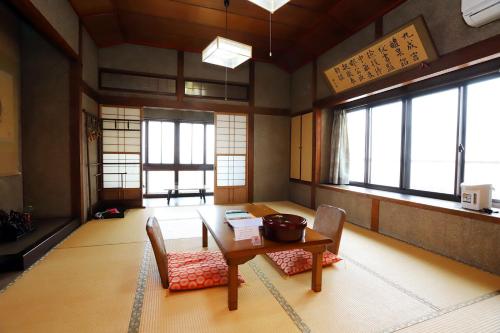 Habitación con mesa, sillas y ventanas. en Hinode Ryokan, en Ise