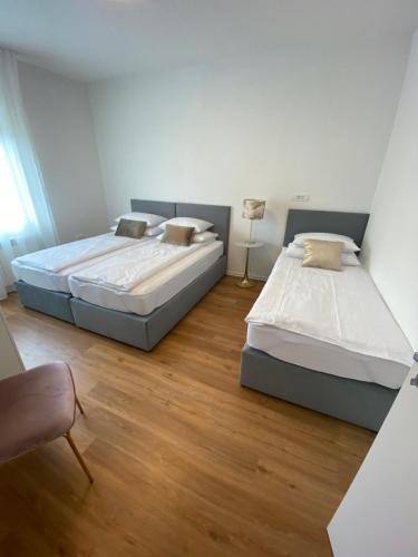 two beds in a room with wooden floors at Apartma pri nani in Kobarid