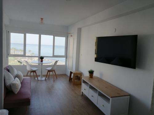 - un salon avec une télévision et une table avec des chaises dans l'établissement HH Apartamento Algarrobo costa, à Algarrobo-Costa
