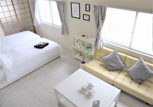a bedroom with a bed and a couch and a table at Osaka U-Shuku in Osaka