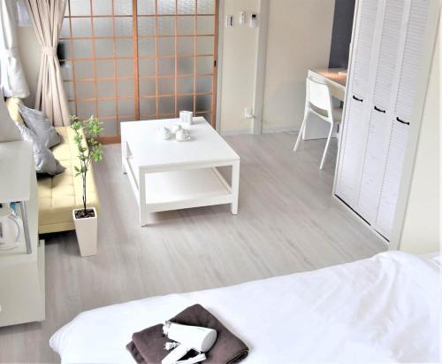 a living room with a white table and a white bed at Osaka U-Shuku in Osaka