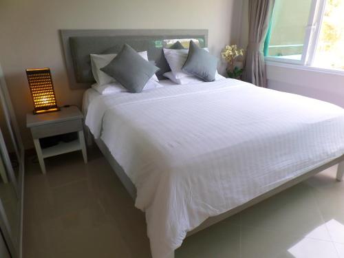 a large white bed in a bedroom with a lamp at Westbury Residence in Pattaya South
