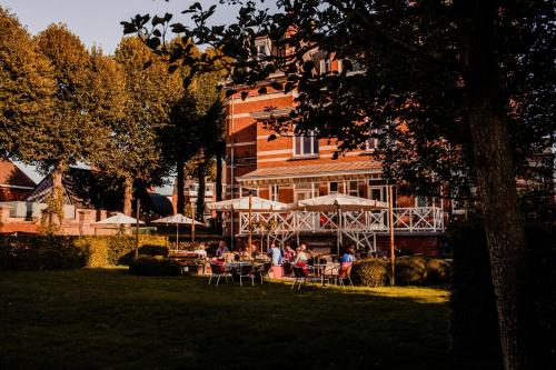 um grupo de pessoas sentadas em mesas em frente a um edifício em B&B 't Kasteel & 't Koetshuys em Veurne