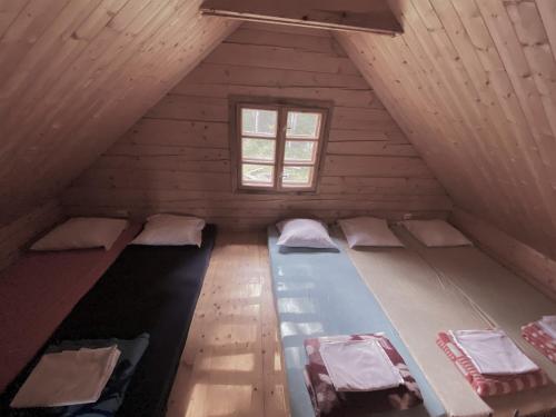 an attic room with three beds and a window at Merkiokrantas Trobelė ant upės kranto in Puvočiai