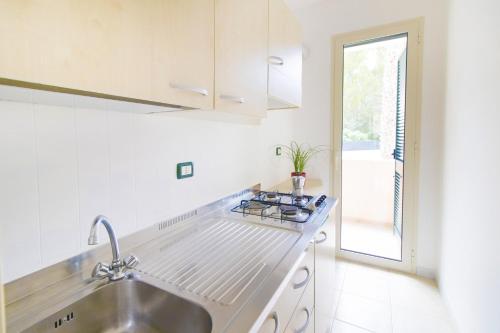 a white kitchen with a sink and a window at Vaia Residence in Torre dell'Orso