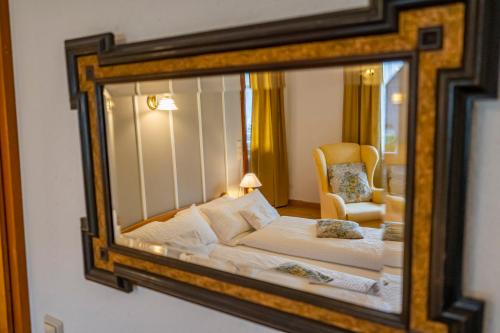a mirror reflecting a bedroom with a bed and a chair at NATURION Hotel Hinterzarten in Hinterzarten