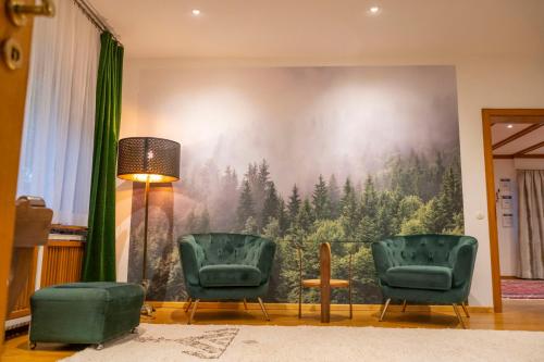 a living room with two chairs and a large painting on the wall at NATURION Hotel Hinterzarten in Hinterzarten