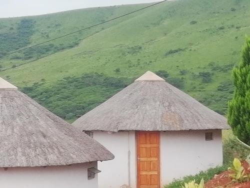 two huts with thatched roofs in front of a mountain at Slubani in Eshowe