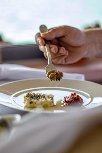 a person holding a spoon with food on a plate at Villa Pietra in Ayvalık