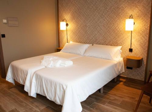 a large white bed with white sheets and pillows at Casa Rico de Medín in O Pino 