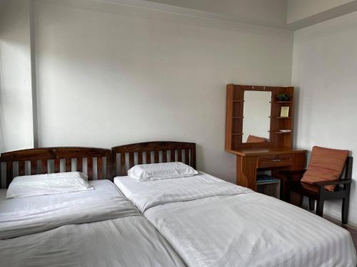 a bedroom with two beds and a dresser and a mirror at Bake Room Hostel in Chiang Mai