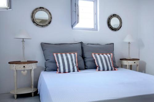 a bedroom with a bed with two pillows and two mirrors at Alfa Luxury Villas in Chrissi Akti