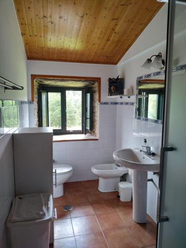 ein Badezimmer mit zwei Waschbecken, einem WC und einem Waschbecken in der Unterkunft Casa O Castelo en Touro in Touro