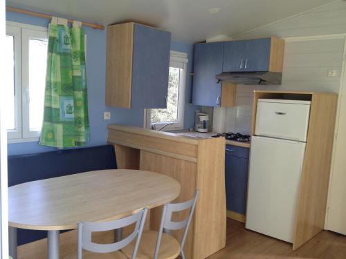 une petite cuisine avec une table et un réfrigérateur dans l'établissement Camping de l'Eouviere, à Montmeyan