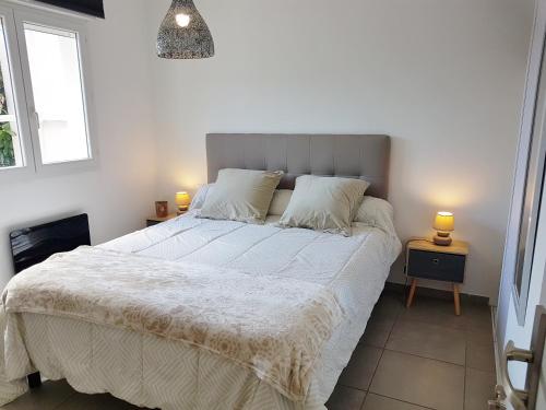 a bedroom with a large white bed with two lamps at SANTA LUCIA in Sainte-Lucie de Porto-Vecchio