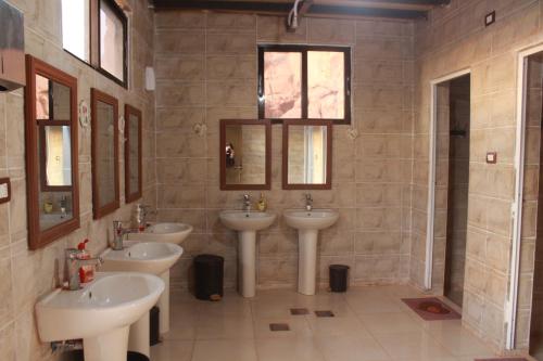 a bathroom with three sinks and two mirrors at Bedouins life camp in Aqaba