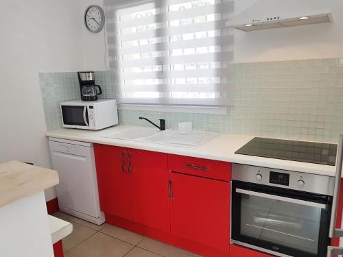 une cuisine avec des armoires rouges et un micro-ondes dans l'établissement SANTA LUCIA, à Sainte-Lucie de Porto-Vecchio