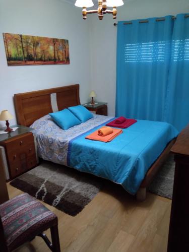 Schlafzimmer mit einem Bett mit blauer Bettwäsche und blauen Vorhängen in der Unterkunft Alto Aguieira in Viseu