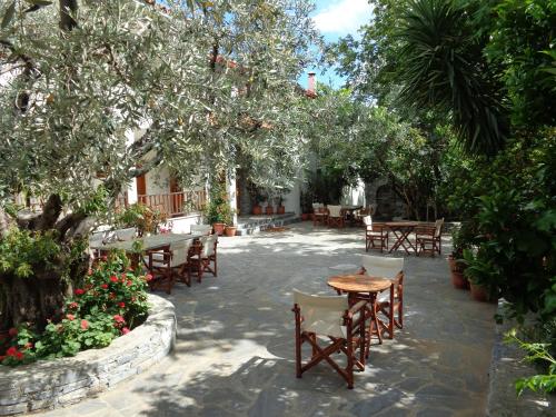 a patio with tables and chairs under trees at Faros in Milopotamos
