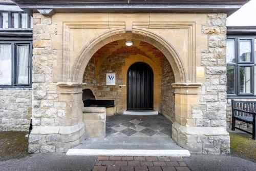 a building with an arch with a door and a bench at Best Western The Webbington Hotel & Spa in Loxton