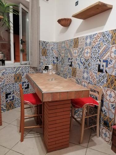 a kitchen with a counter with chairs and tiles at ngopp a via nova in Agropoli