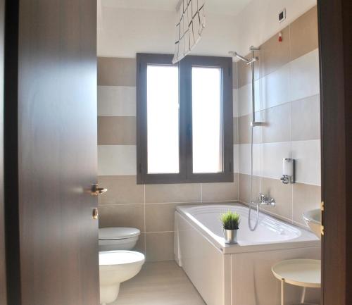 a bathroom with a tub and a toilet and a sink at Verba Mundi Guest House in Olbia